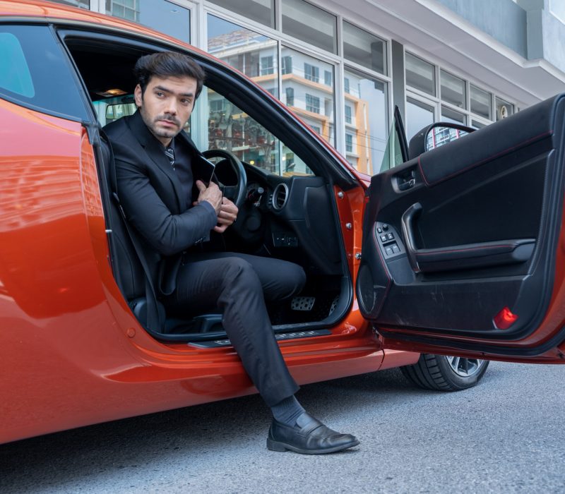 Business people getting out of his sports car.